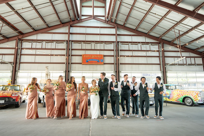 A bride and groom walking with their wedding party inside Saint Arnold Brewing Company. 