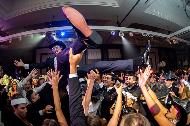 The groom crowd surfs at his wedding grand ballroom reception in Houston.
