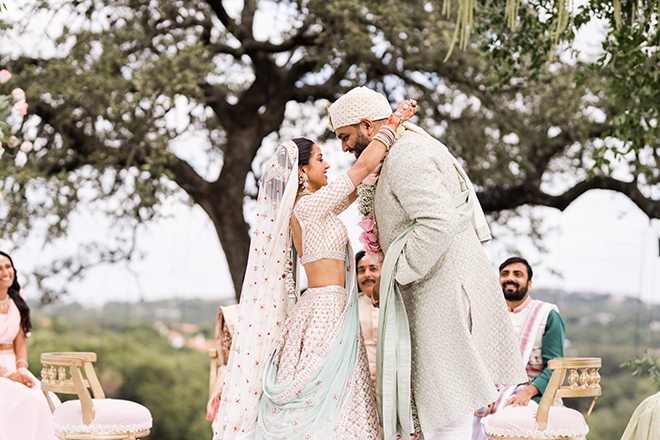 The bride putting floral garland around the groom's neck during the ceremony. 