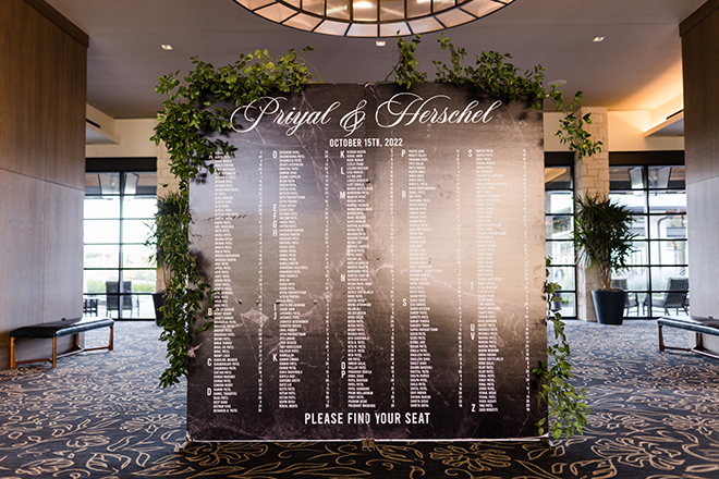 A black table chart with white lettering with "Priyal & Herschel" in cursive. 