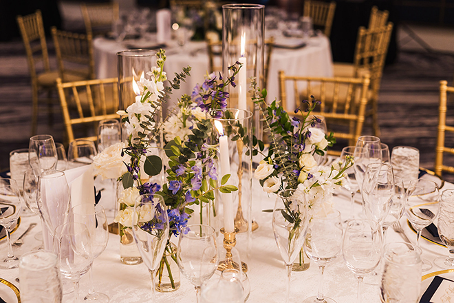 White and blue florals along with lush greenery cover the reception tables at the bride and groom's celebration.