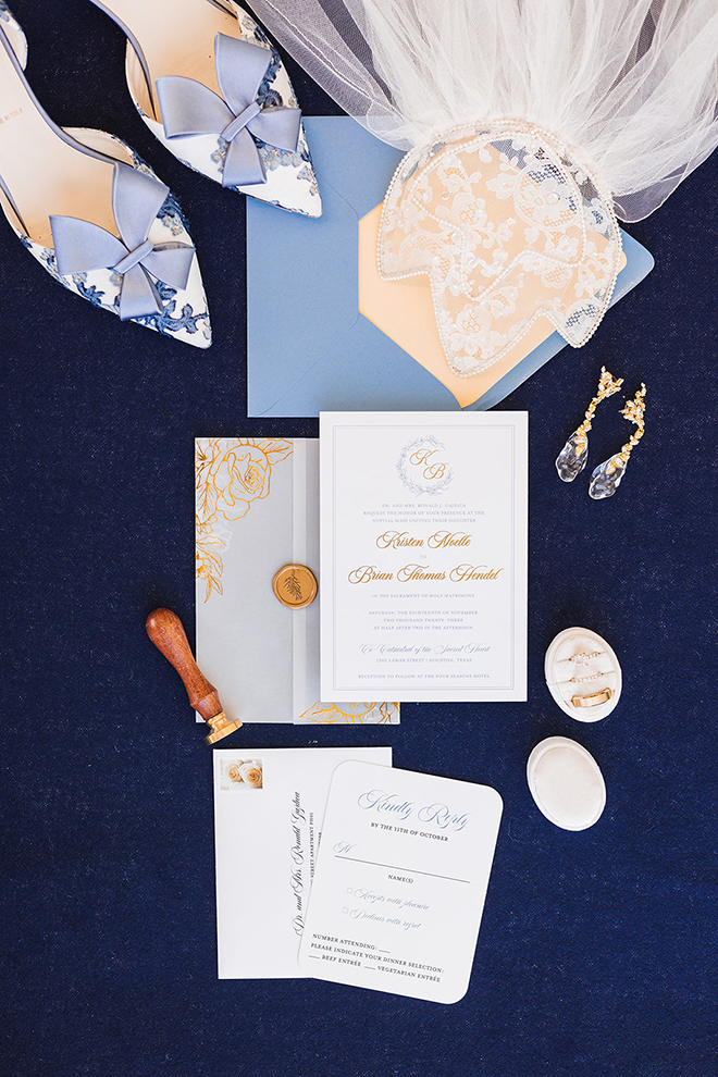 A flat lay of the bride and groom's wedding invitations, jewelry, and veil. 