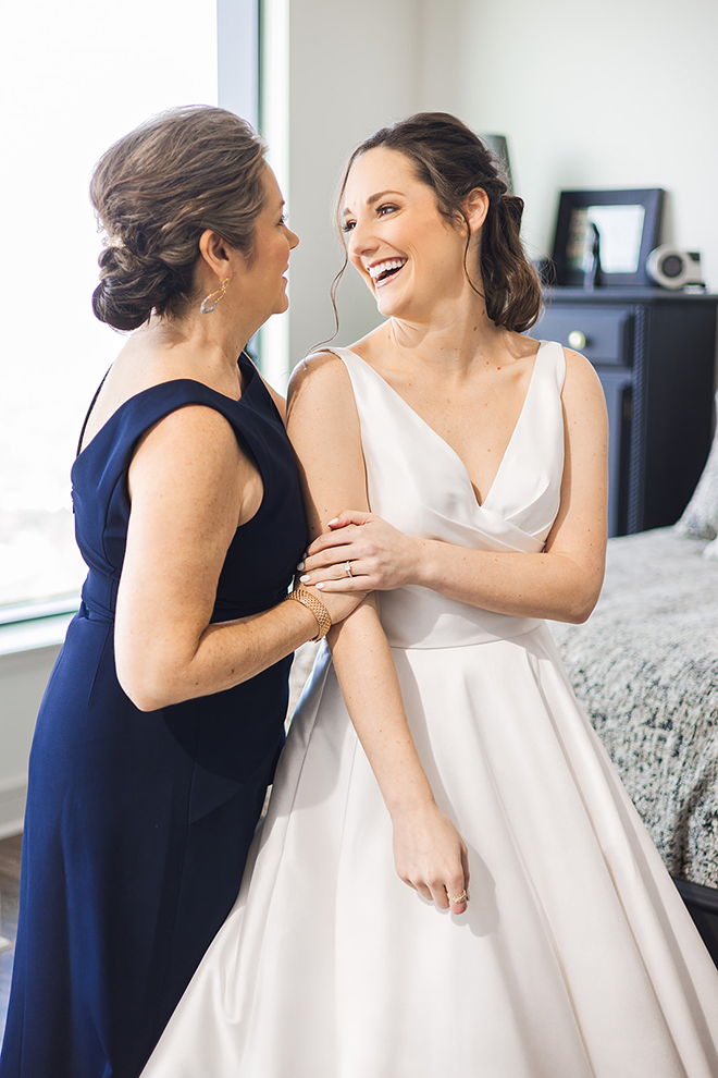 The bride smiles happily at her mother while she gets ready for her big day. 