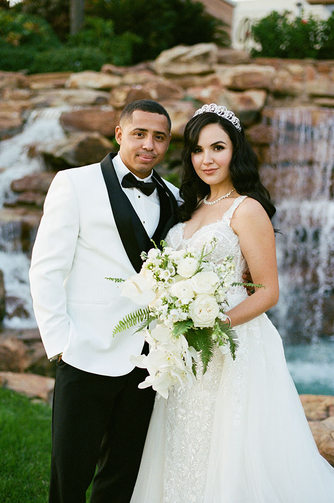 The bride and groom pose in front of a fountain at their beachside wedding at The San Luis Resort, Spa and Conference Center.