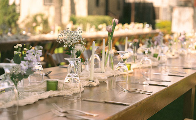 Close view of the set up of the tables, light colored flowers, candles, and glassware. 