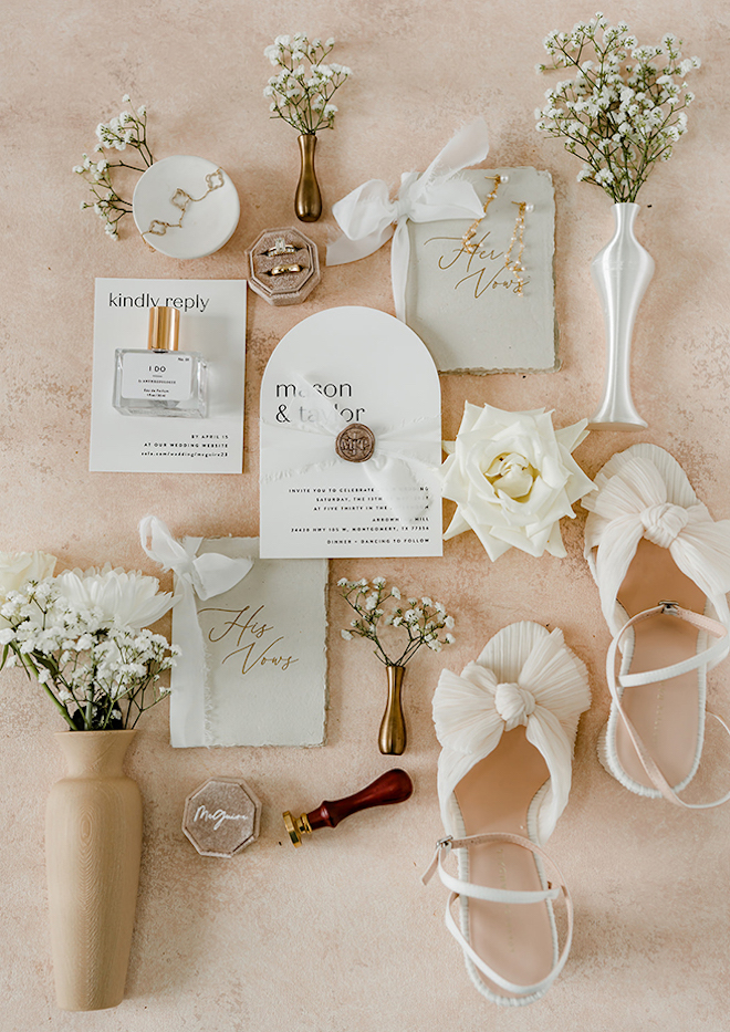 Bride and groom's layout of their wedding invite, rings, and florals. 