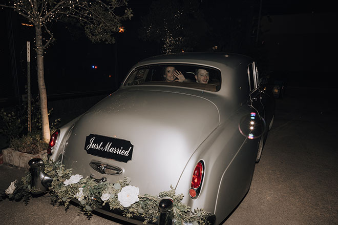 The bride and groom ride off from their wedding reception in a vintage car. 