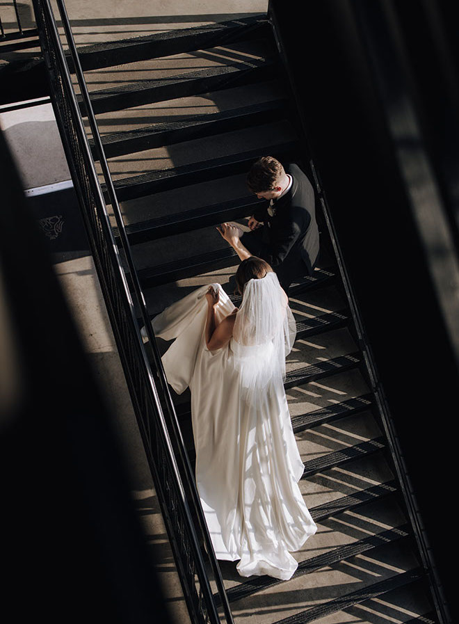 The bride and groom walk up the stairs of their wedding venue, The Astorian.