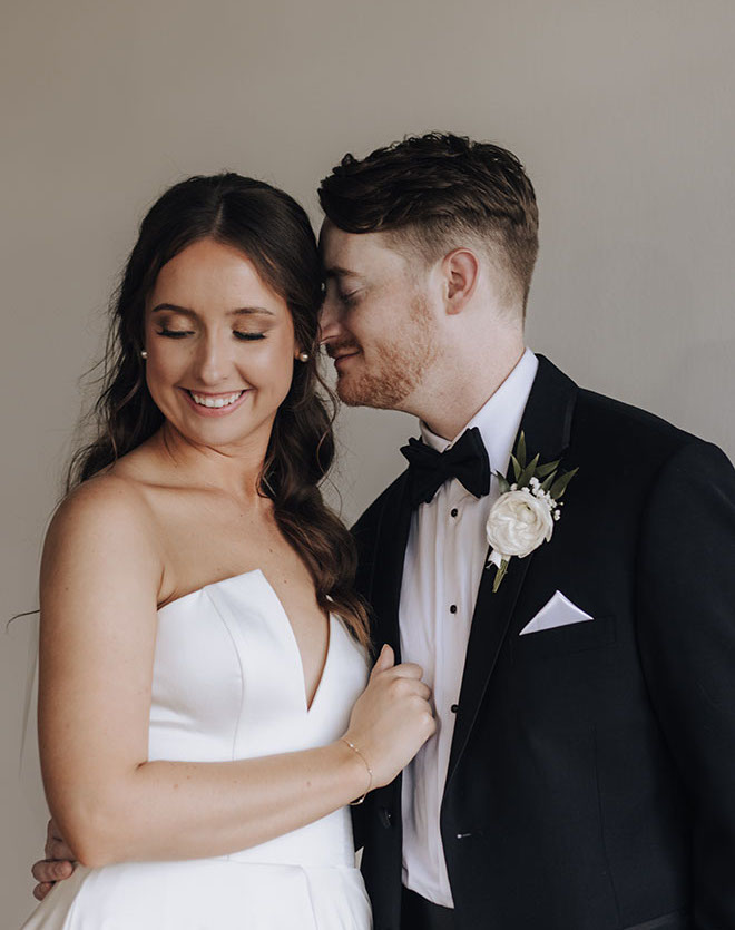 The groom smiles at the bride at their neutral-toned wedding. 