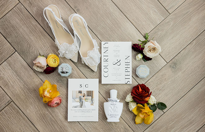 A flat lay of the brides shoes, perfume and wedding stationery. 