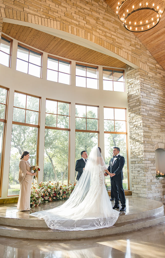 Elizabeth B Photography captures the bride and groom holding hands at the alter.