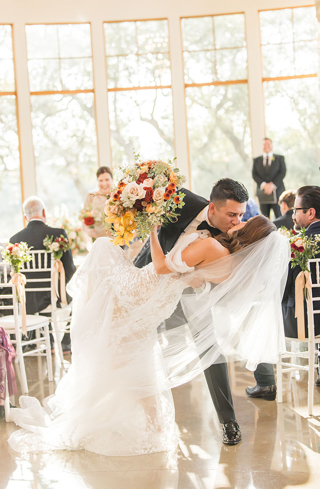 The bride and groom kiss in the aisle at their wedding ceremony.