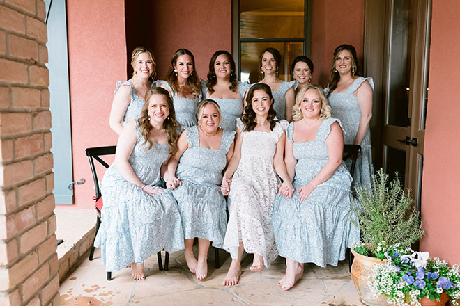 The bridesmaids wear matching blue dresses with florals and patterns. 