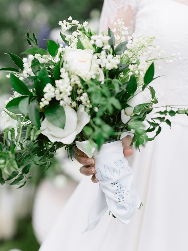 The bride's wedding bouquet is wrapped in a custom handkerchief with her initials on it in blue. 