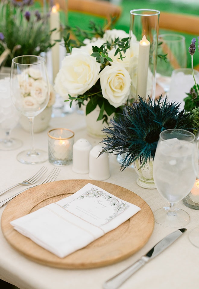 White roses and candles decorate the reception tables at the outdoor tented wedding. 