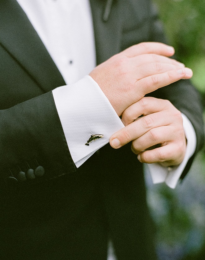 The groom wears fish cufflinks on his tuxedo for the wedding. 