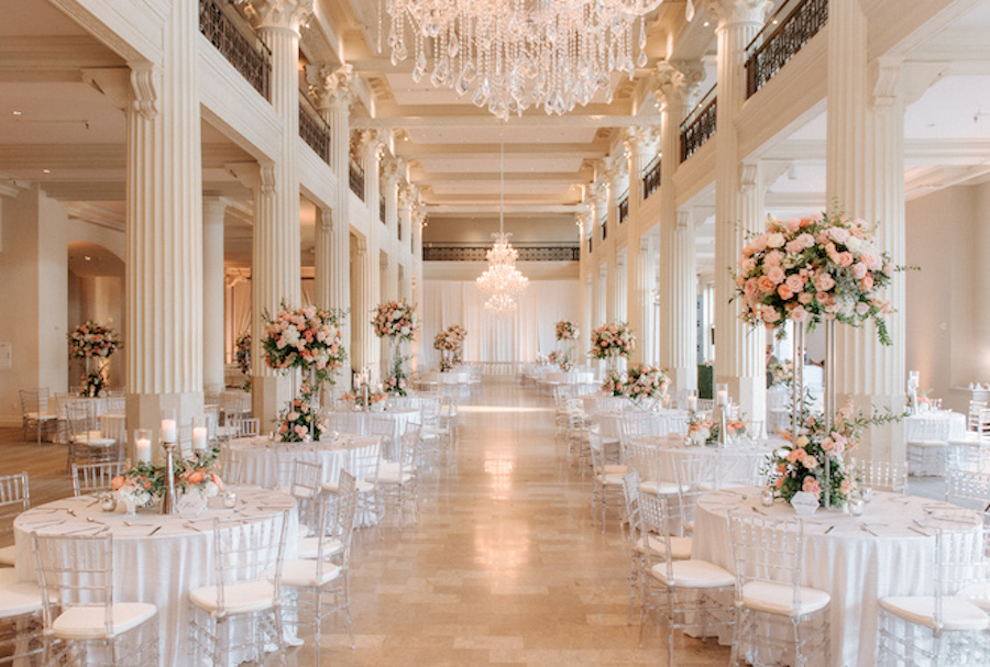 Stunning wedding venue in Houston with tall white pillars and reception tables adorned in pale pink florals. 