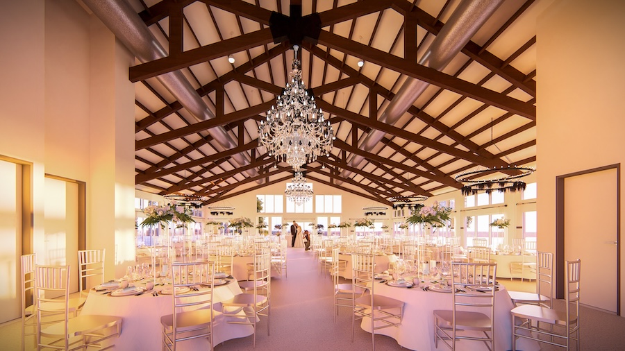 A ballroom venue space with white decorations and a chandelier above reception dinner tables.