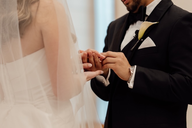 The groom puts the bride's wedding band on her finger during their traditional church ceremony.