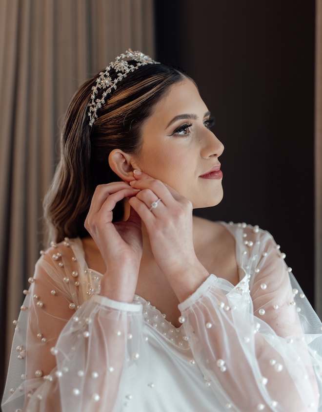 The bride puts on her earrings while getting ready for the wedding ceremony.