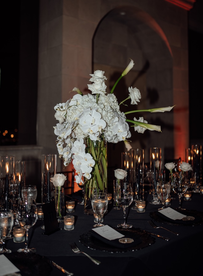 Candles and white flowers decorate the reception tables at the black and white wedding reception.