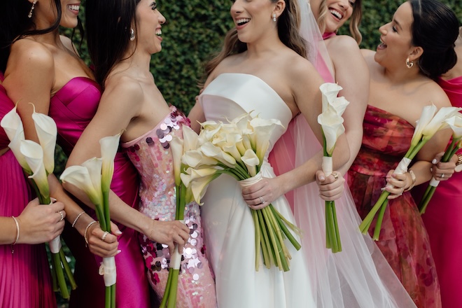 The bride and her bridesmaids hold matching bouquets of lilies for their wedding reception.