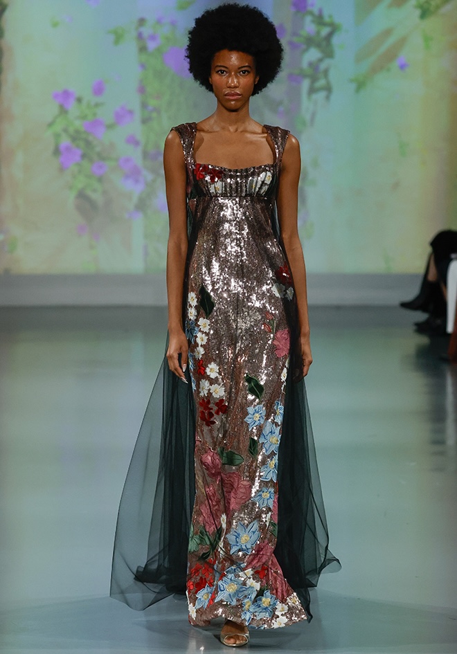 A model walks down the runway while wearing a floral and sequined gown by Ines Di Santo.