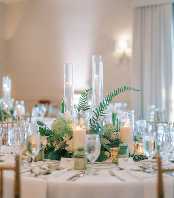 Romantic candlelights, sage green accents, and light blush pink and white florals adorn the reception tables. 