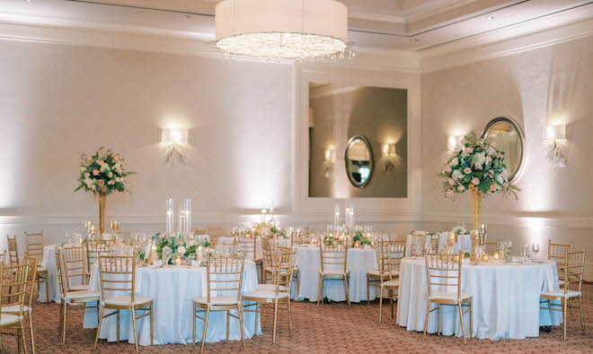 The reception room is filled with gold accents, neutral florals featuring sage green hues and white centerpieces. 