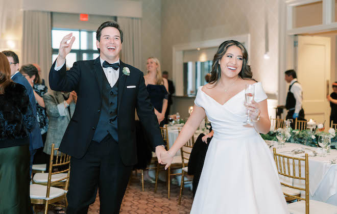 The bride and groom make a grand entrance with a glass of champagne in the brides hand. 