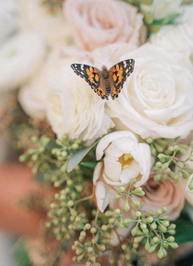 A gorgeous close up photo of the brides bouquet with a monarch butterfly in the middle of the florals. 