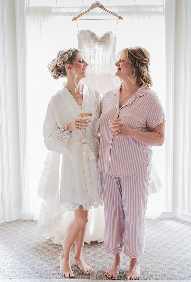 The bride and her mother smile at each other while sipping on Champage.