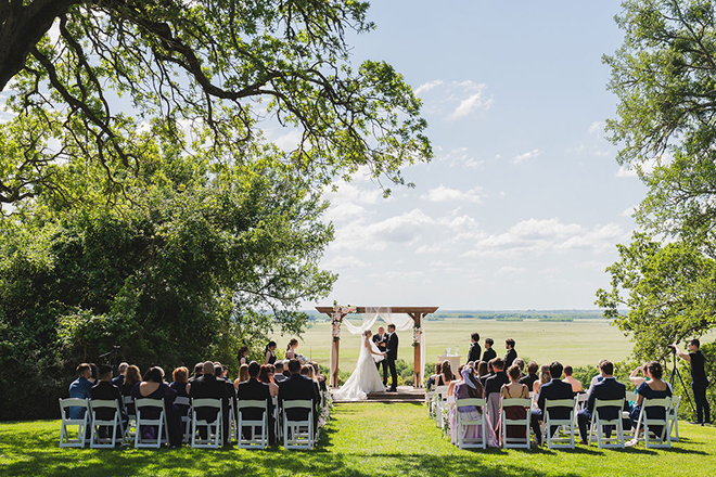 The bride and groom hold hands at the altar at their countryside wedding. 