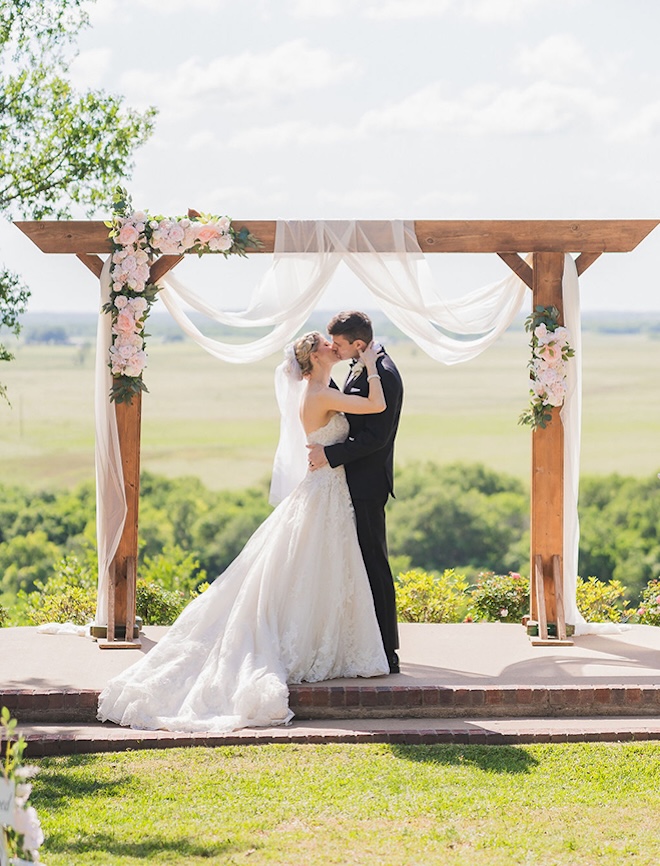 The bride and groom share a kiss at the altar at their outdoor wedding ceremony in Texas. 