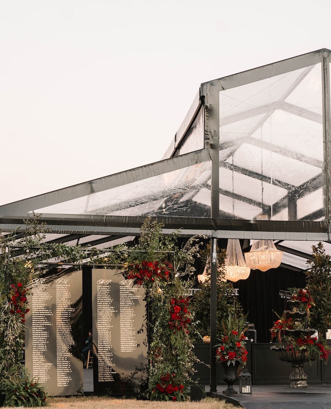 A black-frame tent from Houston Tents and Events hosts an outdoor wedding decorated in red and black colors. 