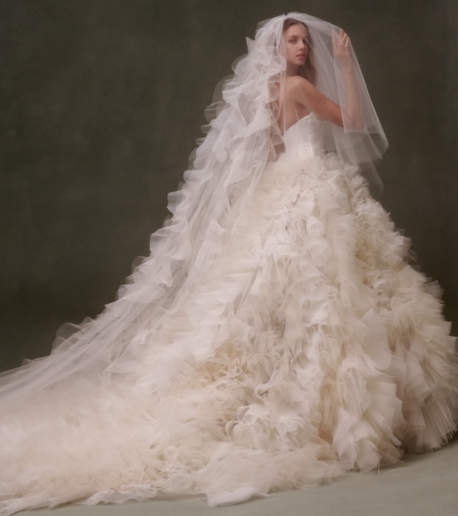 Bride wearing a strapless gown with a ruffle train and a ruffle veil