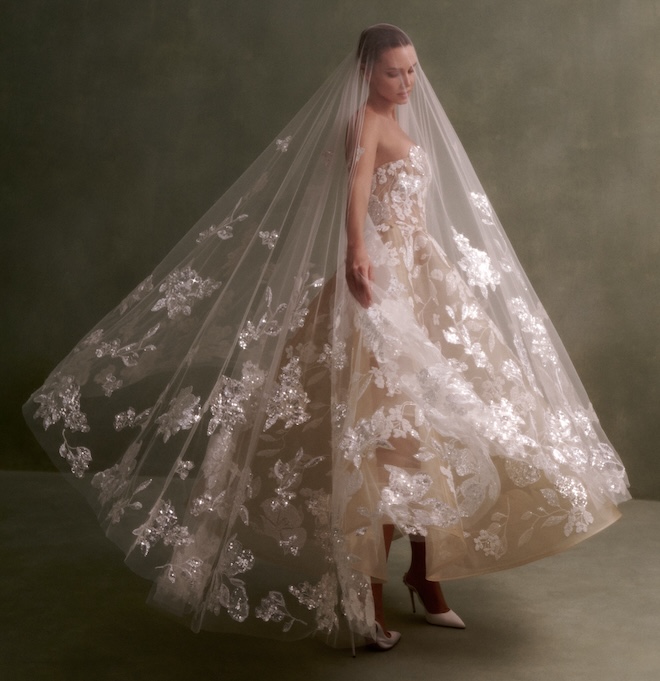 Bride wearing a strapless tea-length dress and veil with beaded flower detail.