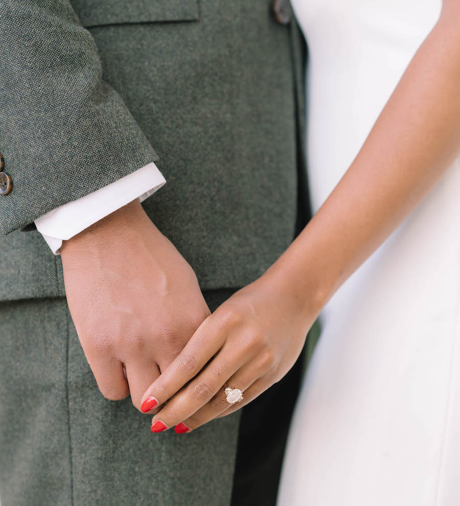 Couple holds hands while posing for engagement photos while dressed nicely. 