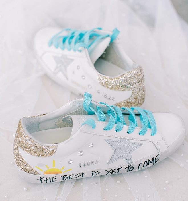 Custom Golden Goose sneakers with blue laces that say "The Best Is Yet To Come" at the bottom of the shoe. 