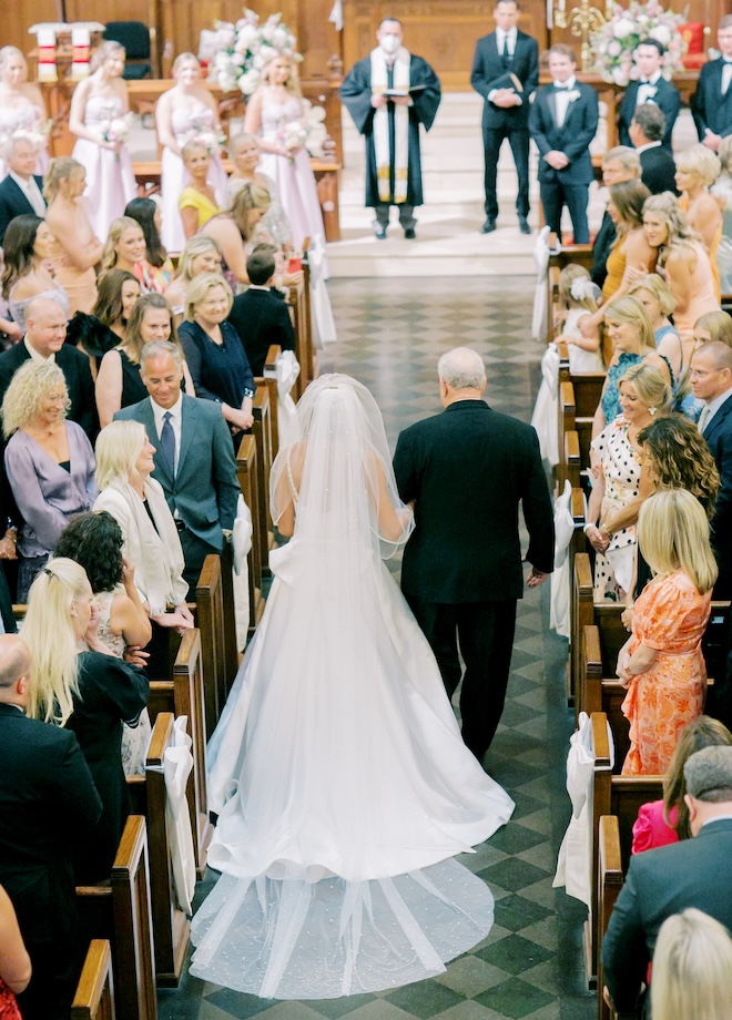 The bride and her father walking down the aisle of the church. 