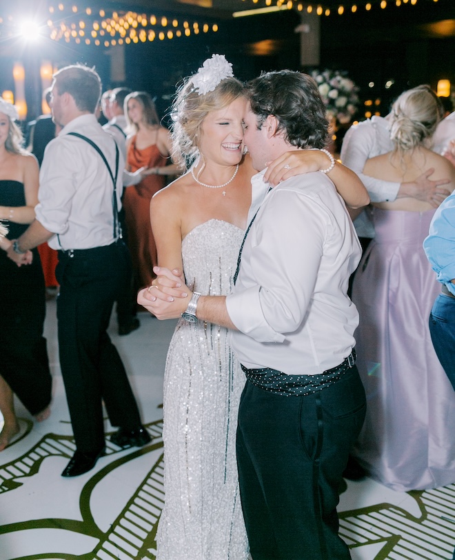 The bride is a strapless sequin gown dancing with the groom on the dance floor. 