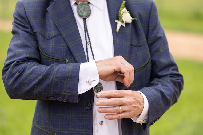 The father of the bride wearing a plaid sport coat, a bolo tie and longhorn cufflinks. 