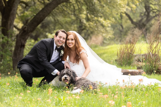 The bride and groom posing with their dog. 