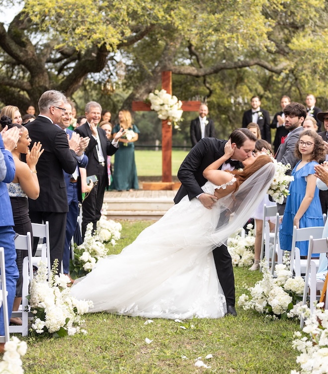 The bride and groom kissing in the middle of the aisle at their ranch wedding. 