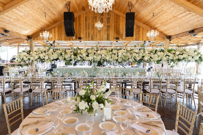 The barn space decorated in white florals and gold chairs. 