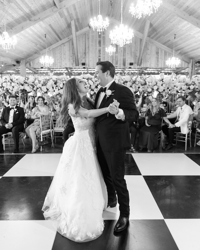 The bride and groom dancing on a black and white checkered dance floor. 