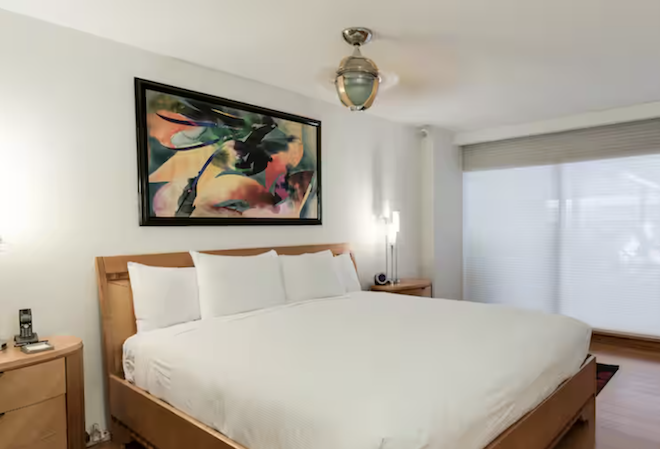 A king bed with artwork over the bed in a hotel suite. 