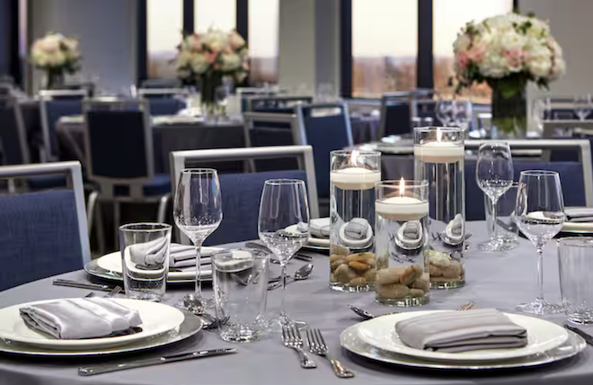 A wedding tablescape with blue linens and chairs and floral centerpieces. 