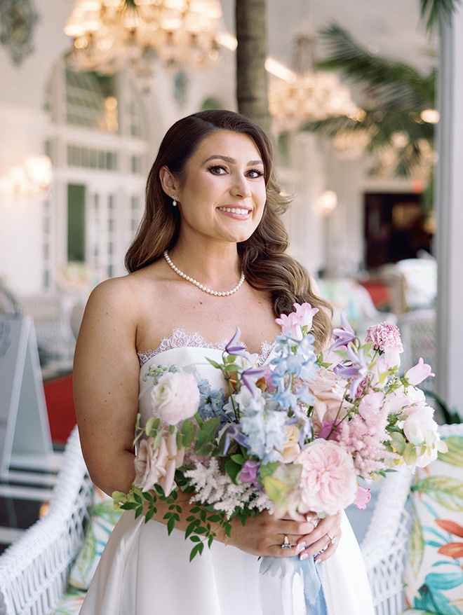 The bride holds her blue and blush colored wedding bouquet. 