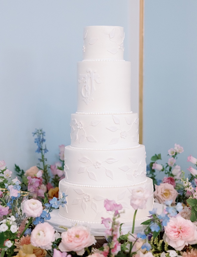 A five-tier white wedding cake designed by Cakes by Gina is the centerpiece of the wedding reception.